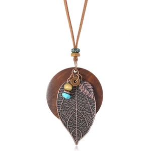 Macro shot of bronze metal leaf and turquoise beads on a wooden disc pendant necklace