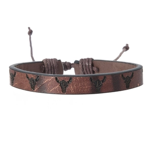 Détail du bracelet tressé en cuir marron foncé avec motif de crâne de bœuf noir