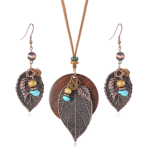 Bohemian retro jewelry set with bronze leaf pendants and wooden disks on white background