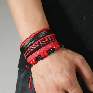 Detail of red and black multi-layer leather bracelets on male wrist in punk style