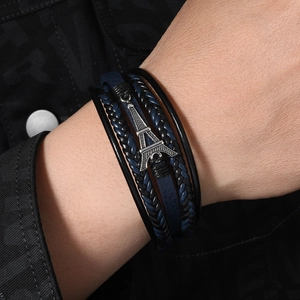 Detail of multi-layer leather bracelet with silver Eiffel Tower charm and braided ropes