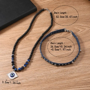 Detail of beaded evil eye pendant necklace with studded denim choker on wood surface