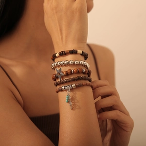 Detail von Boho-Stapelarmbändern mit Holzperlen und Sternanhängern am Handgelenk