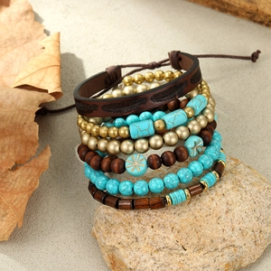 Detail of bohemian layered bracelets with turquoise beads and feather leather on sand