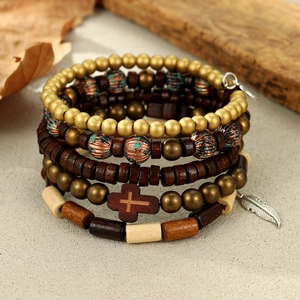 Detailed shot of multi-layer beaded bracelets with wooden cross and metal feather charms