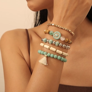 Detail von fünf Boho-Armbändern mit Türkisperlen und Quasten am Handgelenk eines Models