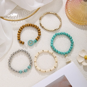 Nahaufnahme eines 5-teiligen Boho-Armband-Sets mit Holz, Türkis und goldenen Akzenten