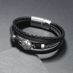 Détail d'un bracelet multicouche en cuir tressé avec breloque foot et fermoir aimanté