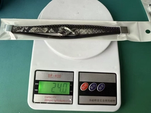 Detail view of multi-layer woven leather bracelet on a digital scale weighing 24.0 grams