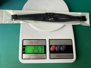 Detail showing deep blue woven leather bracelet with infinity symbol on a scale weighing 25.7g