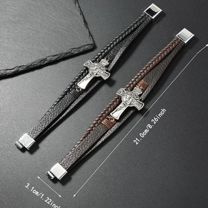 Détail de bracelets multicouches en cuir tressé avec croix et fermoir magnétique