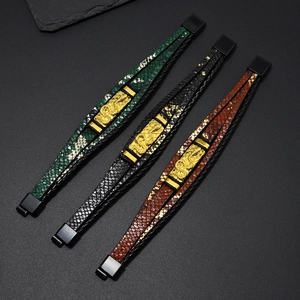 Detail von mehrlagigen Lederarmbändern mit drachengeprägten Goldmetallplatten in drei Farben