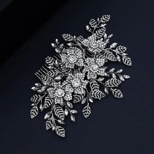 Detailed close-up of a silver bridal hair comb featuring crystal flowers and rhinestones