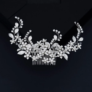 Detail of bridal hair comb with silver metal leaves, white flowers and crystals