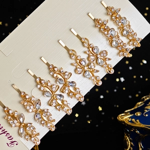 Détail d'un lot de 7 barrettes dorées avec fleurs en strass sur une carte de présentation