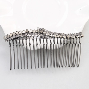 Détail macro d'un peigne à cheveux vintage en strass gris sur une assiette blanche