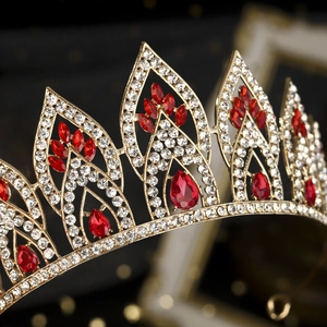 Macro detail of luxury bridal crown with red teardrop crystals and gold alloy setting