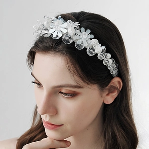 Détail d'un serre-tête floral avec perles blanches et paillettes sur le modèle féminin