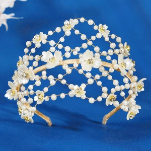 Détail d'un serre-tête de mariée avec fleurs en résine blanche, perles et cristaux dorés