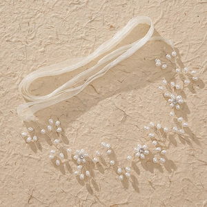 Dettaglio ravvicinato della fascia da sposa con perle bianche e strass brillanti fatti a mano