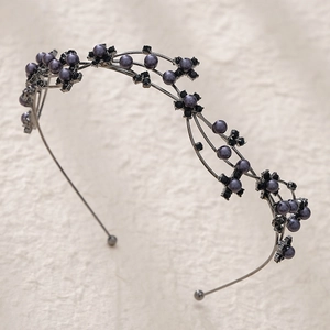 Détail d'un serre-tête rétro avec perles grises et fleurs en diamants noirs