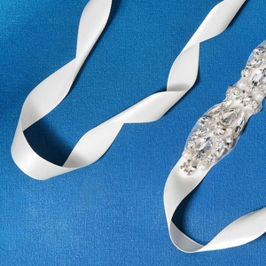Luxurious bridal belt with handmade crystals and pearls on a white satin ribbon