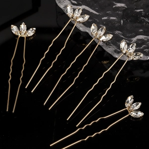 Detail view of 5-piece gold U-shaped hair pins with marquise rhinestones on black surface