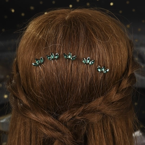 Detailed view of green crystal leaf hair pins set in gold for elegant bridal wedding hairstyles
