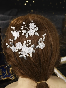 Detailed macro view of bridal hair pin with frosted white flowers and silver leaves