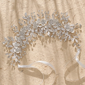 Détail d'un bandeau de mariée argenté avec fleurs en cristal, feuilles et rubans de soie