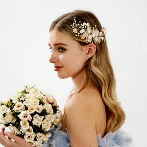 Close-up of bridal hair clip with gold leaves, white flowers, and pearls on model