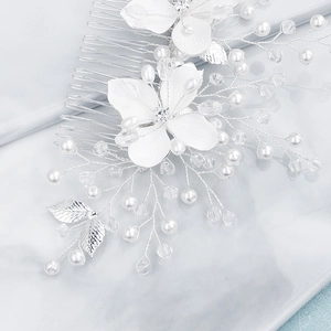 Detail of silver alloy bridal hair comb with matte white flowers and pearl accents