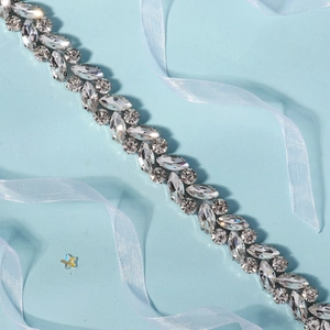 Detail of bridal rhinestone belt featuring marquise cut stones on a soft blue background