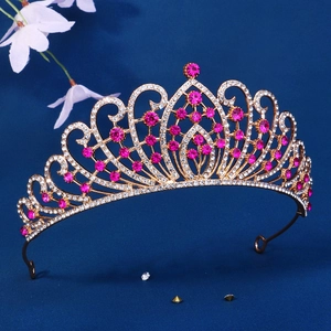 Luxurious gold bridal crown with pink rhinestones and vintage filigree design on blue background