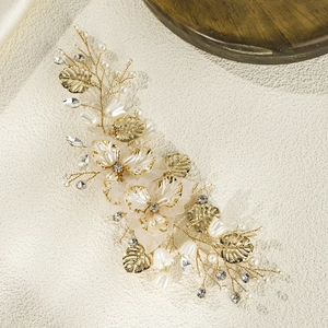 Elegant bridal hair clip with gold leaf, white shell flower and pearls for wedding hairstyle