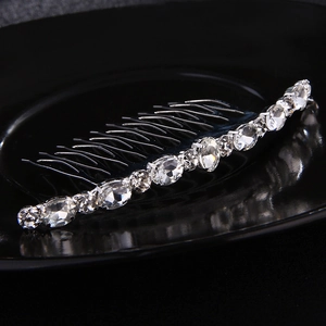 Detail of silver metal hair comb with sparkling oval glass rhinestones on black surface