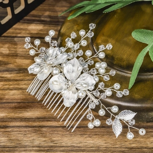 Elegant silver bridal hair comb with metallic flowers, pearls and crystals on dark wood
