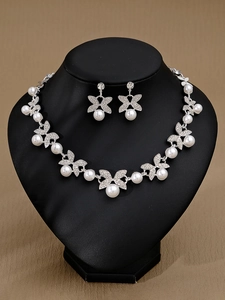 Detailsicht des silbernen Brautschmuck-Sets mit Schmetterlingsmotiven und Perlen auf Büste