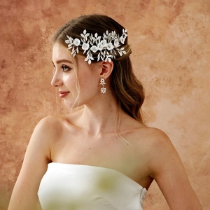 Detail of white flower bridal hair comb and drop earrings set worn by a bride