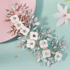 Detail of white matte floral hair clip with crystals and silver leaves for bridal styling