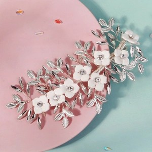Close-up of white flowers and crystal leaves on silver bridal hair clip accessory