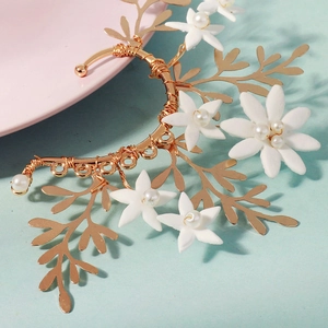 Detail of handmade gold floral ear cuff featuring white flowers and pearls on wire