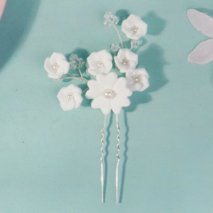 Detail of bridal hair pin with handmade white clay flowers and pearls on silver metal