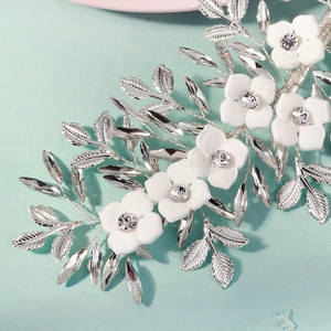 Detail of white ceramic flowers and marquise crystals on silver bridal hairpiece