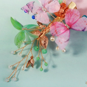 Détail de la pince à cheveux papillon en tulle rose et vert avec perles de cristal