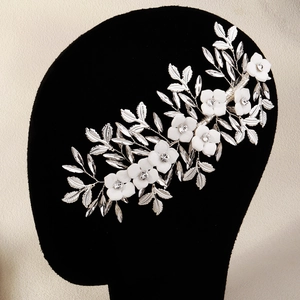 Macro detail of white floral bridal hairpiece with pearls and silver leaf accents