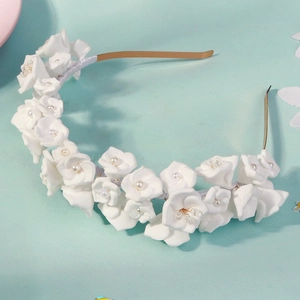 Gros plan sur un serre-tête de fleurs blanches fait main avec base dorée et perles fines