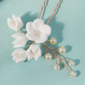 Detail view of handmade clay flower hair pins with pearls and golden wires for brides