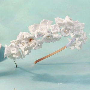 Détail de fleurs en céramique blanche avec perles et cristaux sur serre-tête doré