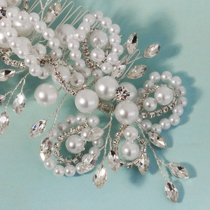 Close-up of handmade bridal hair comb with pearls and rhinestones on blue surface